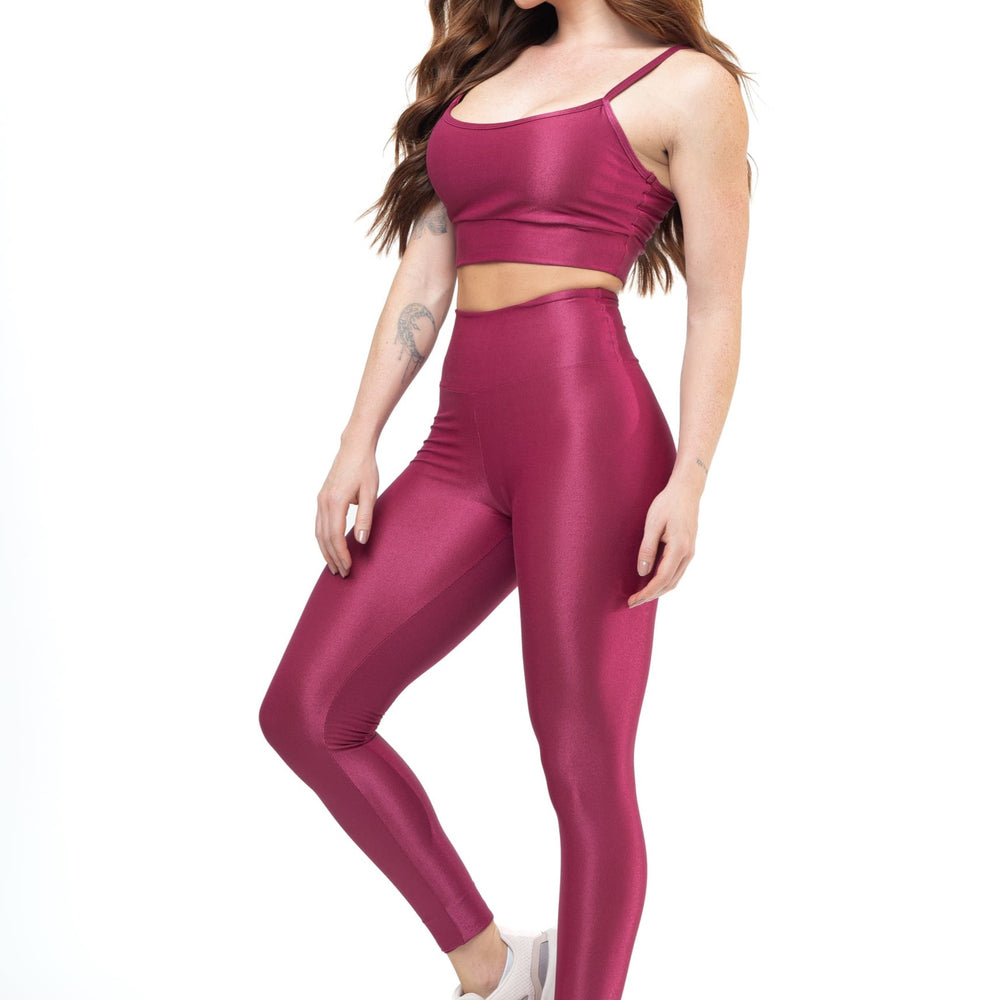 
                  
                    Woman in magenta workout set—crop top with thin straps and high-waisted leggings—paired with pink sneakers. Ideal for gym or casual wear.
                  
                