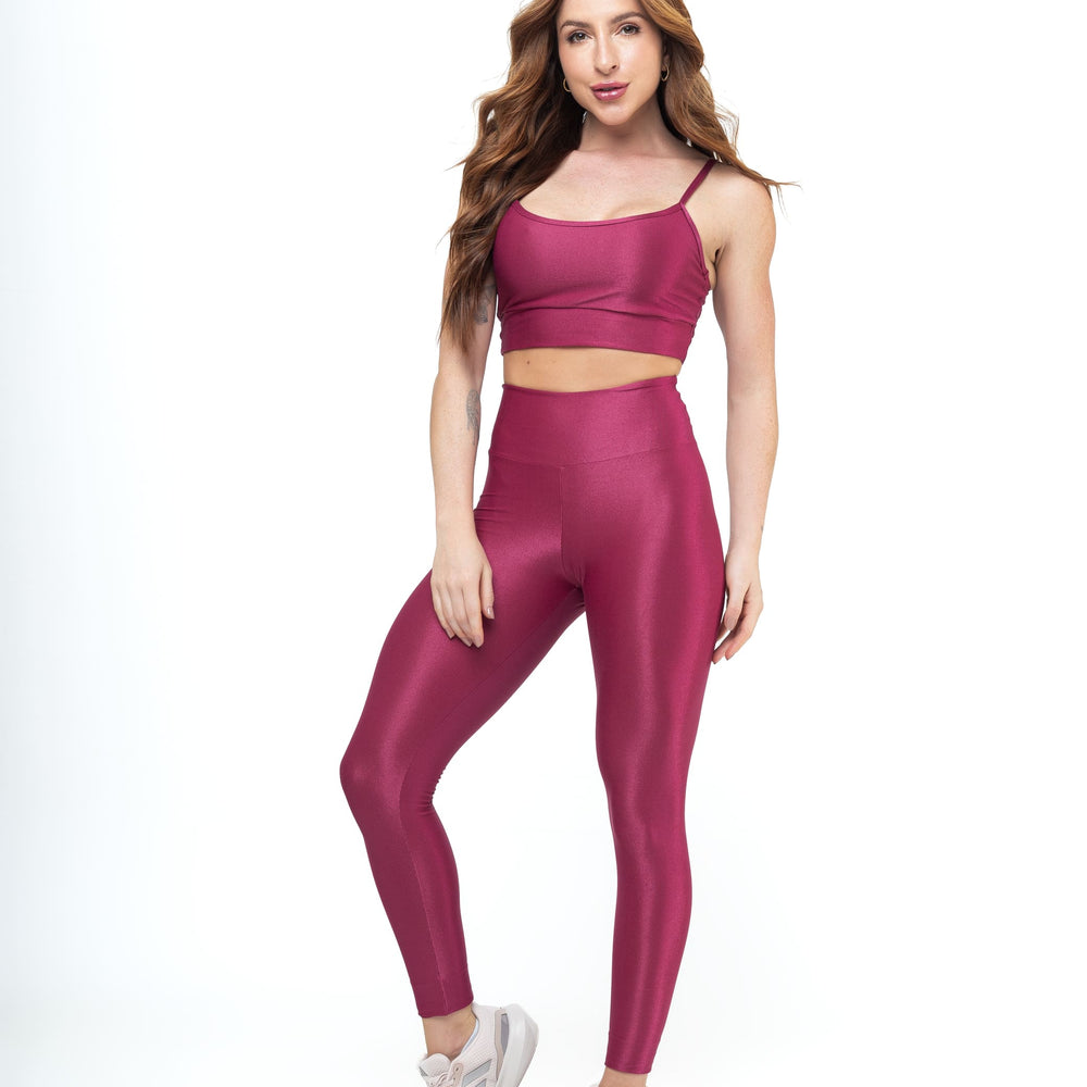 
                  
                    Woman in magenta workout set—crop top with thin straps and high-waisted leggings—paired with pink sneakers. Ideal for gym or casual wear.
                  
                